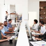 Office workers at shared desks using desktop computers