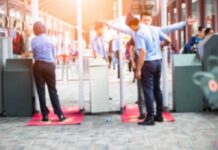 Security officers screen people at walk-through metal detectors