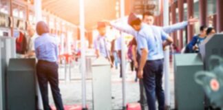 Security officers screen people at walk-through metal detectors