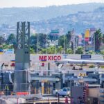 Mexican President Threatens To Sue After Illegals Shot By ICE Border crossing booths at Mexico entry point with cityscape in background