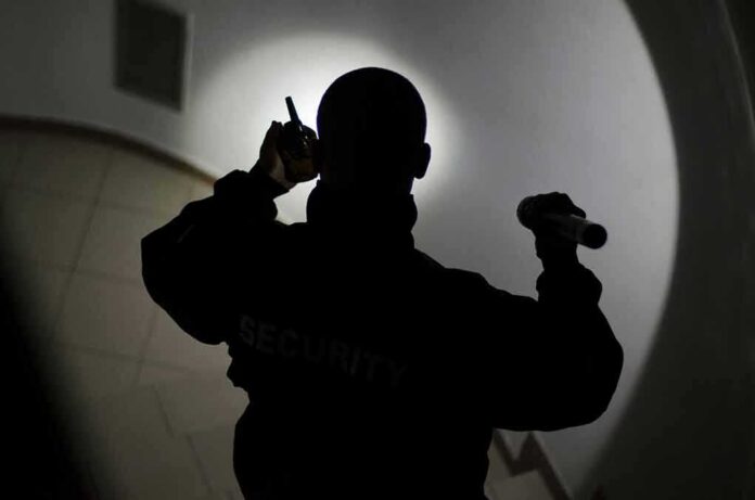 shutterstock_774954514 Security guard with flashlight and radio in dim hallway