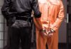 3 A.M. Raid Foils Violent Capitol Plot Prisoner in orange jumpsuit handcuffed with guard standing beside
