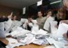 People counting ballots at a table