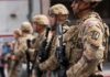 National Guardsman Shot Breaking Up Fight Soldiers in camouflage gear stand in formation holding rifles