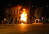 Street fire at night with bystanders near a burning object