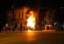 Street fire at night with bystanders near a burning object