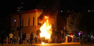 Street fire at night with bystanders near a burning object