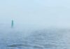 Green buoy in foggy sea