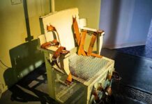 Electric chair with leather restraints in a dim room