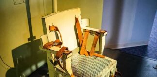Electric chair with leather restraints in a dim room