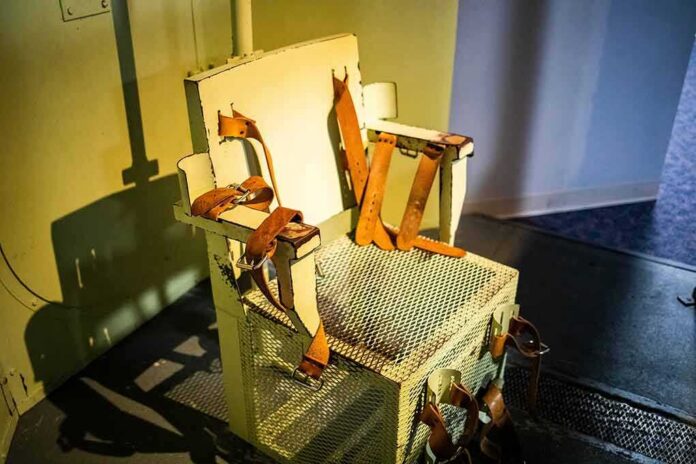 shutterstock_1949329633 Electric chair with leather restraints in a dim room