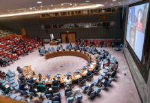 Trump Slaps ICC After Ex-Judge Wins Nobel Delegates seated around a circular conference table in a large chamber