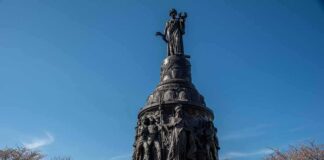 Bronze monument with allegorical figures under a clear blue sky