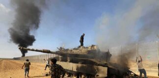 Burned tank with people around it in a desert area