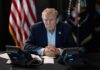 Trump Invokes Executive Privilege Over THIS Donald Trump seated at a table between two desk phones