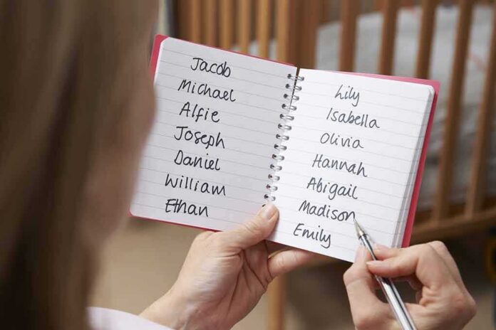 Hands holding a notebook with baby name lists near a crib