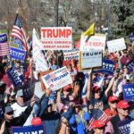 Tim Teufel, Christian Jones, and Nash the Slash among a crowd at a political rally holding signs and flags