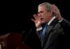 George W. Bush speaking at a podium with hands raised