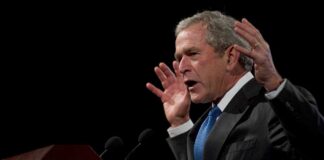 George W. Bush speaking at a podium with hands raised