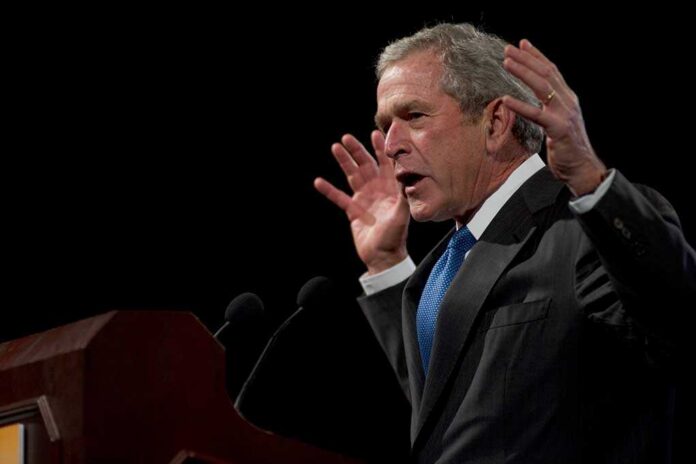 George W. Bush speaking at a podium with hands raised